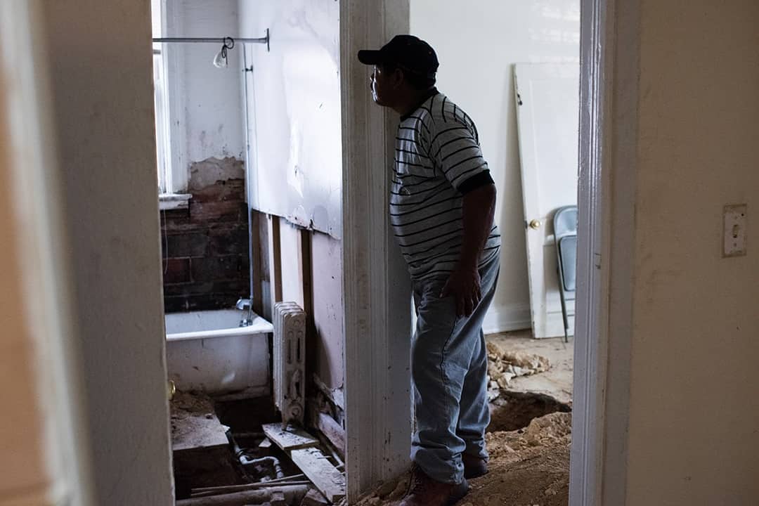 Javier Grijalva, 53, standing inside his first apartment in a building, which had crumbling walls, molds, and very hot pipes running through the floor.